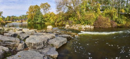 Foto de Serena mañana de otoño en Huron River, Michigan, con un puente cubierto rústico y una cascada rocosa - Imagen libre de derechos