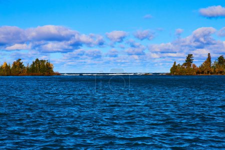 Vibrant daytime view of Lake Superior during fall at Copper Harbor, Michigan featuring serene blue waters and lush island greenery