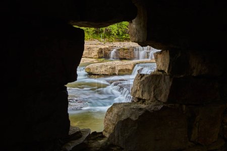 Serene Cataract Falls scene from cave opening in Indiana, featuring flowing river and cascading waterfalls, embodying tranquility and natural beauty