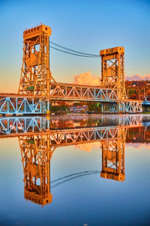 Foto de Golden Sunrise Over Portage Lake Lift Bridge en Houghton, Michigan - Majestuosa estructura de acero que reflexiona sobre el agua tranquila en el otoño de 2017 - Imagen libre de derechos