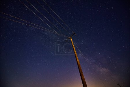 2017 Indiana night sky showcases Perseid meteor shower beyond a towering telephone pole, underscoring human connectivity and cosmic grandeur.