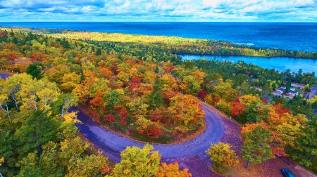 Impresionante vista aérea del vibrante paisaje otoñal en Copper Harbor, Michigan, mostrando un camino sinuoso, un follaje denso de otoño y un lago expansivo