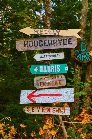 Photo for Whimsical handmade signs nailed to tree in lush Michigan forest during fall season, pointing directions to rural family homes - Royalty Free Image