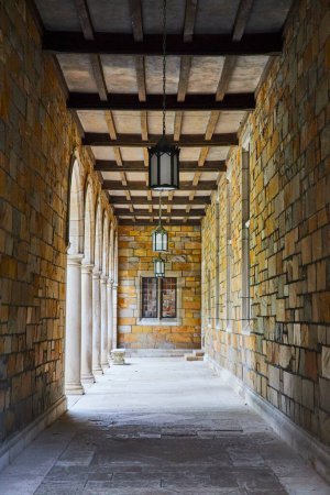 Ruhiger Korridor mit eleganten Bögen und rustikalen Steinwänden im University of Michigan Law Quadrangle, der zeitloses architektonisches Design und Geschichte widerspiegelt