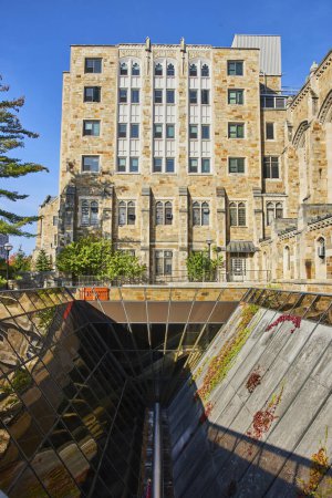 Gothic-style University of Michigan building contrasts with modern underground entrance in Ann Arbor campus scene