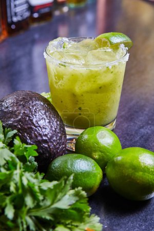 Erfrischender grüner Cocktail in einem eleganten Glas, garniert mit Limetten und umgeben von frischen Zutaten, in einer trendigen Tapas-Bar in Fort Wayne, Indiana, 2017.