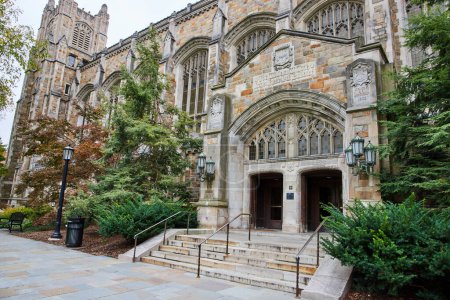 Entrée du bâtiment de style gothique de l'University of Michigan Law Quadrangle à Ann Arbor, accentuée par une riche maçonnerie de pierre et une végétation luxuriante.