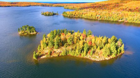 Luftaufnahme des beschaulichen Medora-Sees in Michigan mit lebendigem Herbstlaub und heiterer Insel, aufgenommen per Drohne im Jahr 2017