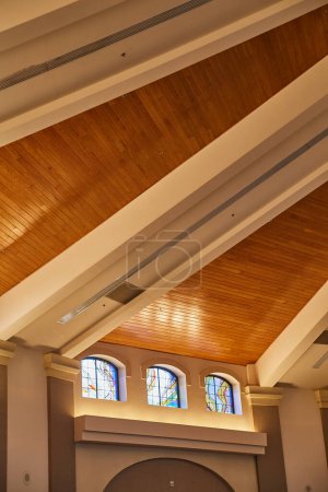 Photo for Interior of a building in Fort Wayne, featuring warm wooden ceiling, white beams, and stained glass windows, blending modern and traditional design - Royalty Free Image