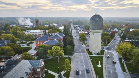 Photo for Early morning aerial view of historic Ypsilanti Water Tower overlooking a tranquil suburban street in Michigan, USA, set against a soft sunrise skyline. - Royalty Free Image