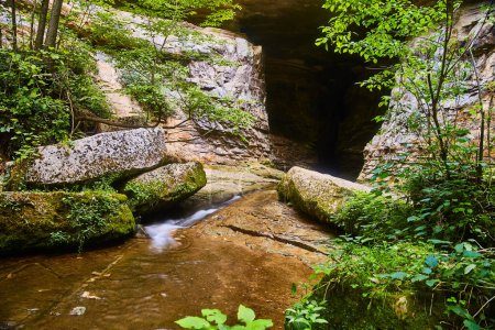 Serene long exposure of a gentle waterfall flowing into Donalds Cave at Spring Mills State Park, Indiana, showcasing natures untouched beauty.