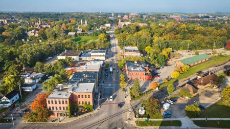 Photo for Aerial view of a peaceful Michigan town in early autumn, showcasing architectural diversity and a main road, captured by a DJI Mavic 3 drone. - Royalty Free Image