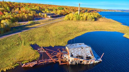 Aerial view of dilapidated industrial structure amidst vibrant autumn foliage in Houghton, Michigan