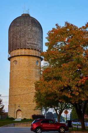 Historic Ypsilanti Water Tower in Michigan at Golden Hour, with vibrant autumn foliage and modern red SUV
