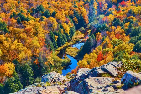 Lebendiges Herbstlaub über einem ruhigen Fluss in Lake in the Clouds, Michigan, von einem hohen Aussichtspunkt aus eingefangen.
