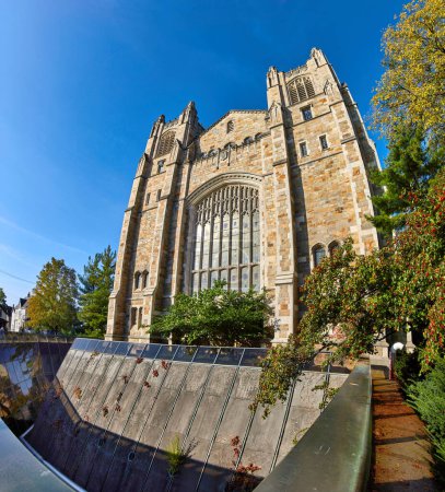 Foto de Arquitectura de renacimiento gótico en University of Michigan Law Quadrangle, Ann Arbor, destacado por el follaje de otoño y reflexiones modernas bajo un cielo azul claro - Imagen libre de derechos