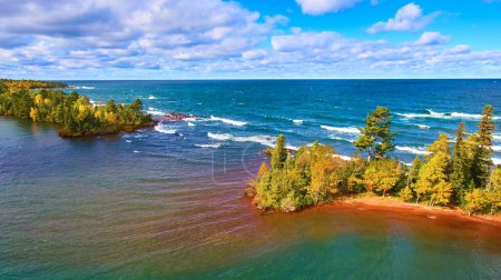 Aerial drone view of an autumnal coastline in Copper Harbor, Michigan revealing a vast Lake Superior under soft, late afternoon light.
