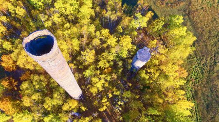 Aerial view of abandoned industrial chimneys amid vibrant autumn forest in Houghton, Michigan