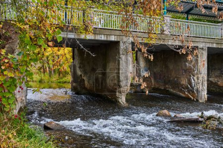 Autumn Colors Enveloping Aged Pedestrian Bridge Over Tranquil River in Homer, Michigan