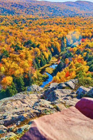 Vivid fall foliage in Ontonagon County, Michigan, 2017. A high-angle view from Lake in the Clouds overlook, showcasing the beauty of autumn with a winding river flowing through the vibrant landscape.