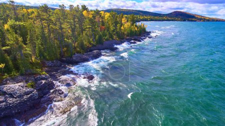 Luftaufnahme der zerklüfteten Küste des Lake Superior in Copper Harbor, Michigan, mit lebendigem Herbstwald und dynamischer Wasserbewegung, aufgenommen von der DJI Phantom 4 Drohne im Jahr 2017