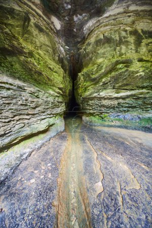 Mysterious view inside Donalds Cave, Indiana, featuring rugged rock formations and tranquil stream