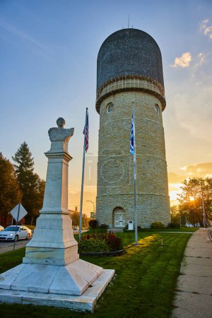 Sunset paints a golden hue on the historic Ypsilanti Water Tower and statue, amidst a serene Michigan town backdrop