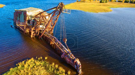 Graffiti adorned abandoned dredge, bathed in late afternoon sunshine, languishing in Michigans waters - a striking symbol of industrial decay and natures resilience.