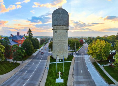 Historic water tower in Ypsilanti, Michigan bathed in golden hour light, with surrounding urban landscape and vibrant fall foliage.
