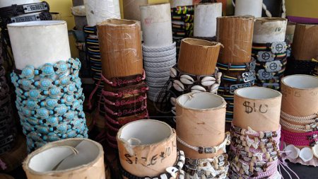 Vibrantes pulseras hechas a mano exhibidas en un puesto de mercado tropical, con simbolismo cultural y atractivos recuerdos de playa.