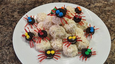 Verspieltes Arrangement spinnenartiger Leckereien auf einem weißen Teller, ideal für Kinderfeste oder Halloween-Feiern