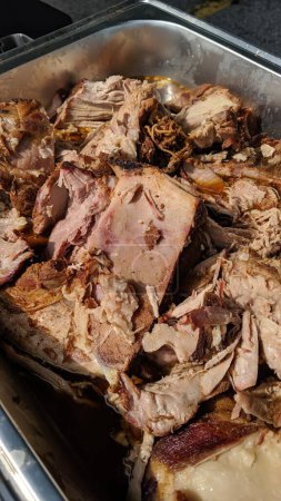 Freshly cooked pulled pork in a metal container, perfect for catering, barbecue or comfort food themes