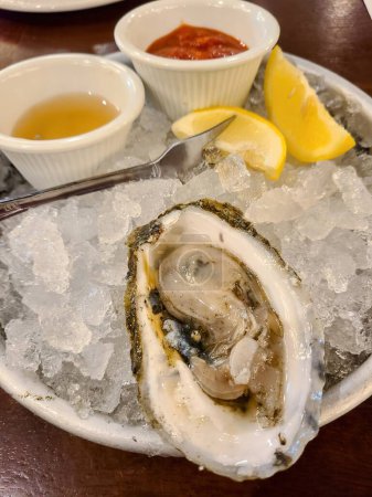 Erhöhter Blick auf ein Gourmet-Austerngericht, serviert mit Gewürzen und Zitrusfrüchten auf Crushed Ice, mit luxuriösen Meeresfrüchten in einem Restaurant in Massachusetts, 2022
