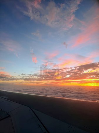 Breathtaking aerial view of vibrant sunset over the Bahamas, captured from an airplane window above a serene cloud cover