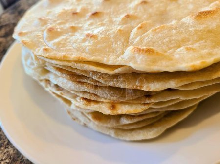 Freshly made stack of Mexican Tortillas on a white plate in a bright home kitchen, Fort Wayne, Indiana, 2022