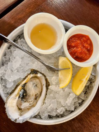 Delicias frescas de ostras sobre hielo, servidas con condimentos y cuñas de limón, en un restaurante gourmet en Worcester, Massachusetts, 2022