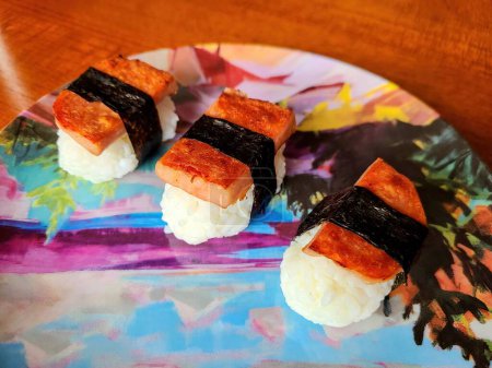 Eye-level shot of three pieces of gourmet sushi artfully prepared on a floral plate, in a home setting in Fort Wayne, Indiana during Christmas 2021, promoting healthy eating and Japanese cuisine.