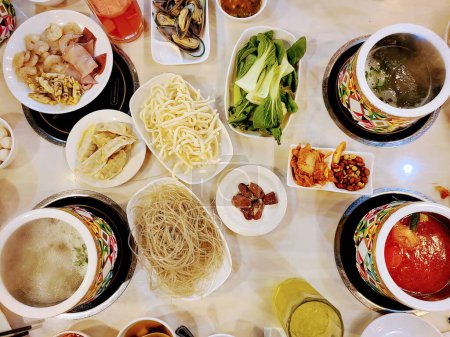 Overhead view of a vibrant hot pot feast showcasing variety of fresh ingredients at a Bloomington, Indiana restaurant, 2022
