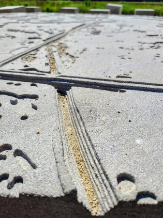 Abstrakte Installation von Textured Concrete Art in Killdeer Wetlands, Illinois, 2022 - Eine Nahaufnahme einer verwitterten Betonstruktur mit komplizierten Stadtplan-Designs unter natürlichem Licht
