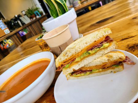 Freshly prepared bacon, avocado, and cheese sandwich with tomato soup in a cozy San Francisco cafe at Fort Mason, epitomizing hearty comfort food.