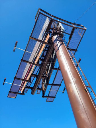 Upward view of an intricate billboard tower, against a bright blue sky in Muncie, Indiana, 2023 - embodying media, advertising, and communication.