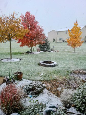 Der frühe Schneefall staubt die lebendigen Herbstbäume in einem ruhigen Hinterhof in Fort Wayne, Indiana, 2021