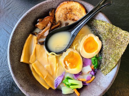 Inviting bowl of traditional Japanese ramen with vibrant ingredients, served in a stylish grey bowl against a dark background, Warsaw 2023