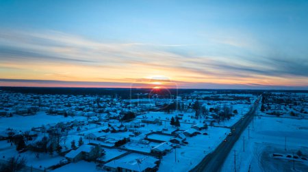 Wintersonnenuntergang wirft einen goldenen Schein über einem friedlichen, schneebedeckten Viertel in Fort Wayne, Indiana