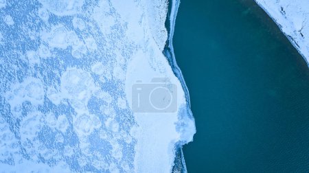 Luftaufnahme eines ruhigen, schneebedeckten Fort Wayne, Indiana, wo eisige Landschaft auf tiefblauen See trifft, ein Winterwunderland im Herzen Amerikas.