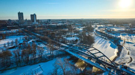 Winternachmittag zieht über Fort Wayne, Indiana, und wirft goldene Farbtöne auf die schneebedeckte Martin Luther King Bridge und die Skyline der Innenstadt.