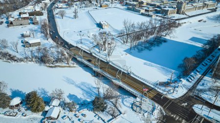 Aerial view of snowy Fort Wayne, Indiana featuring the Veterans Memorial Bridge over the St. Marys River in winter