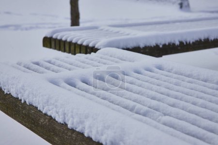 Serene winter scene in Fort Wayne, Indiana, showcasing the natural beauty of a snow-draped park bench in tranquil Freimann Square.