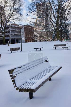 Heiterer Winter in der Innenstadt von Fort Wayne, Indiana - frischer Schnee bedeckt einen ruhigen Stadtpark mit historischer Uhrturmkulisse