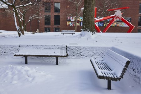 Mantas de nieve recién caídas Serene Park con escultura de arte rojo moderno en el centro de Fort Wayne, Indiana
